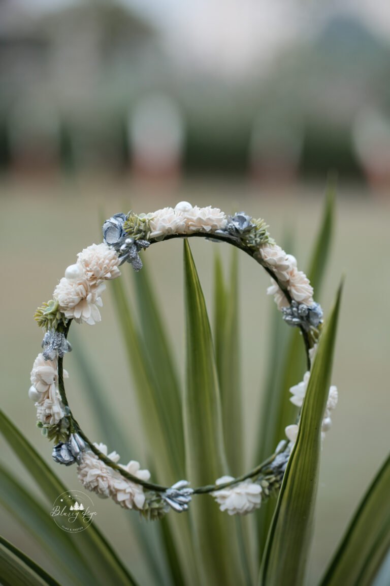 Handcrafted baptismal crown or tiara for a baby, set against a backdrop of lush greenery outdoors.