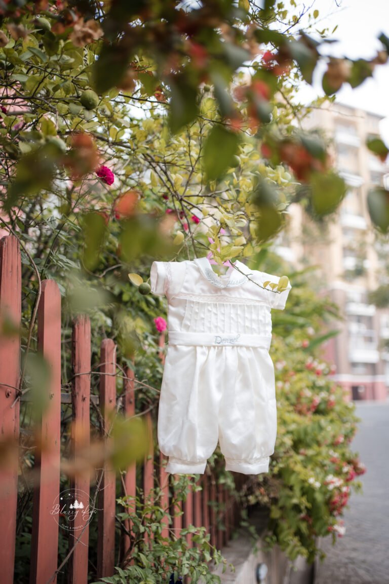 Photo of a baptismal outfit featuring a white boy romper with lace details