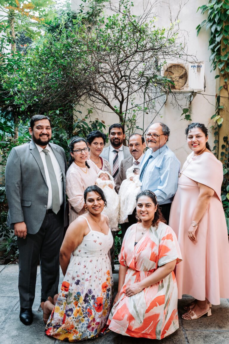 Three generations of a family posing for a portrait in their courtyard on a baptism day morning.