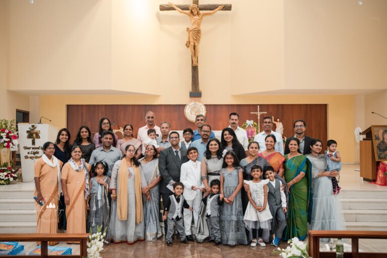 Large group of people posing for a photograph in front of a church altar during a baptism ceremony.