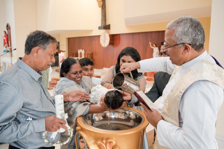 Priest performing baptismal ceremony, pouring water onto the head of a newborn baby in Pune India.