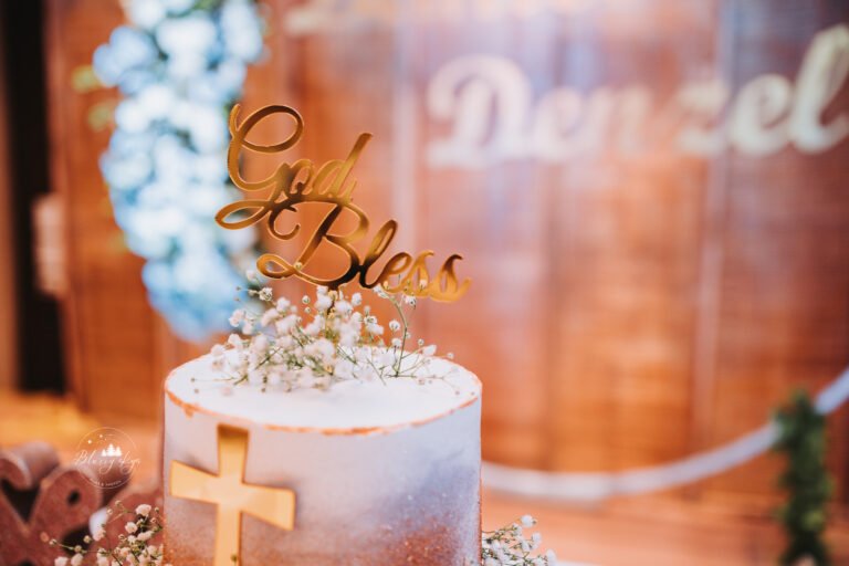 Beautifully decorated baptism reception cake adorned with flowers, a Holy Cross, and the baby's name.