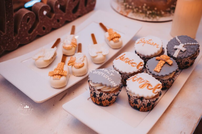 Set of beautifully decorated cupcakes on a table next to the cake for a baptism reception.