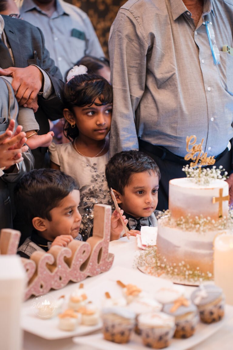 Two naughty little brothers playfully fighting over the cake during their younger brother's baptism reception cake cutting.