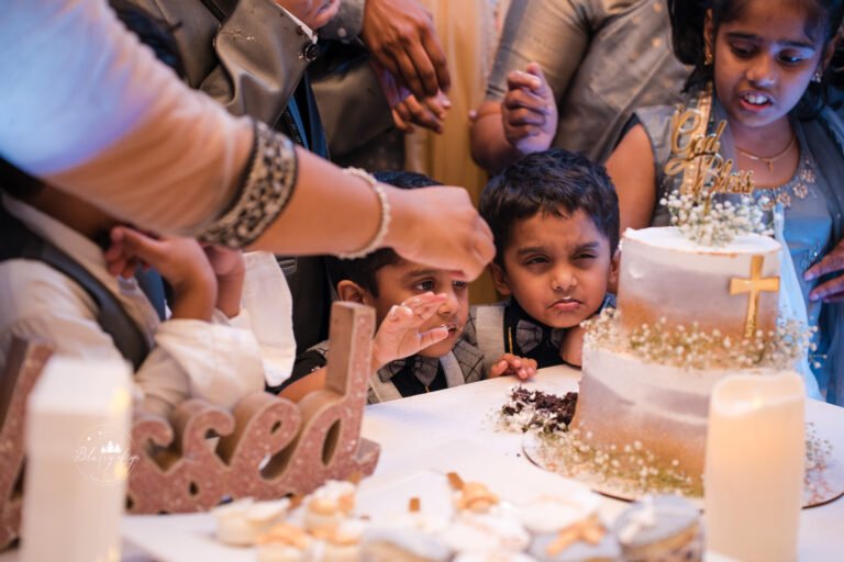 Two naughty little brothers playfully fighting over the cake during their younger brother's baptism reception cake cutting.