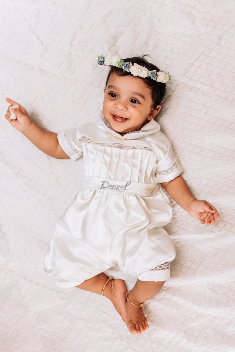 Cute baby portrait captured on baptism day morning. Baby is wearing a tiara/crown and smiling.