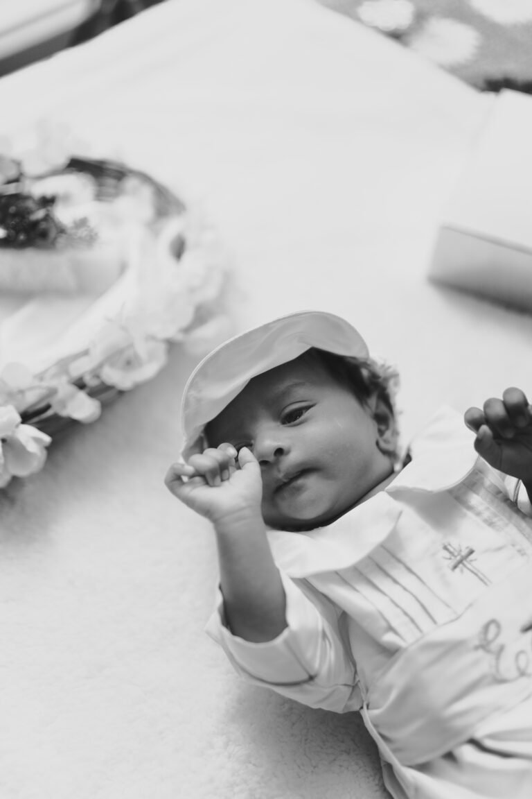 Candid photo of a newborn baby with baptismal accessories such as cane basket in the background.