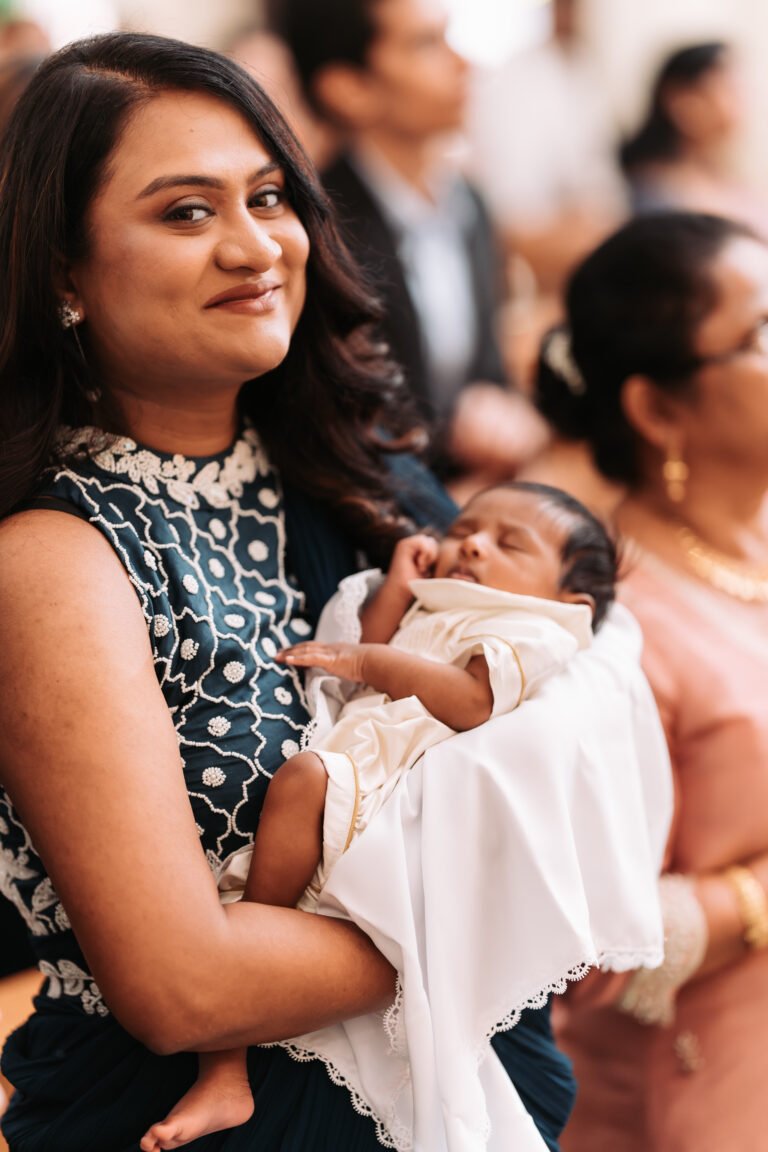 An image of a mother holding her cute little child in the church on a baptism day.