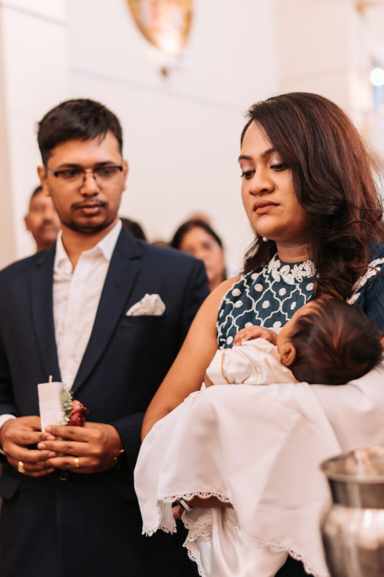 Parents praying for their child in church during the baptism ceremony.