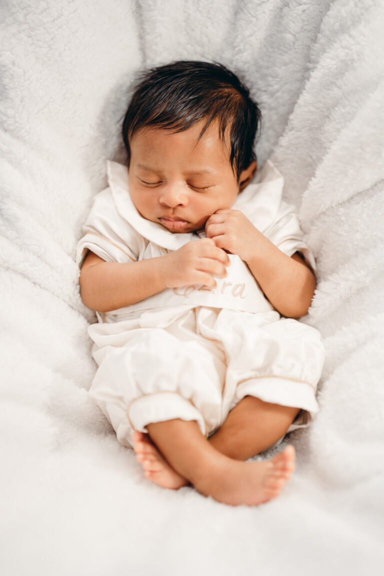 Cute little child peacefully sleeping in a crib during his baptism reception.