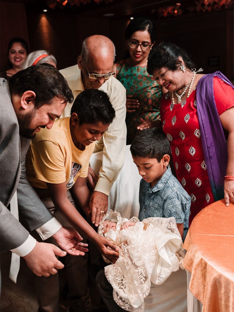 Little boy holding a baby carefully, surrounded by family