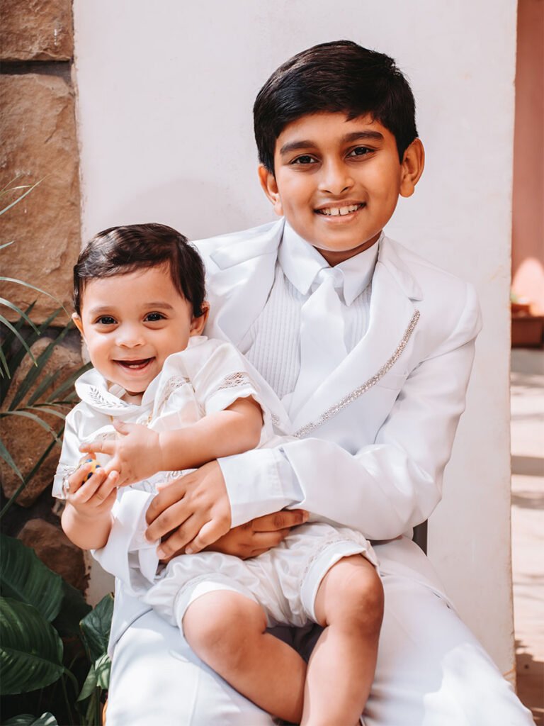 Young boy tenderly holding his newborn brother in his arms on baptism day.