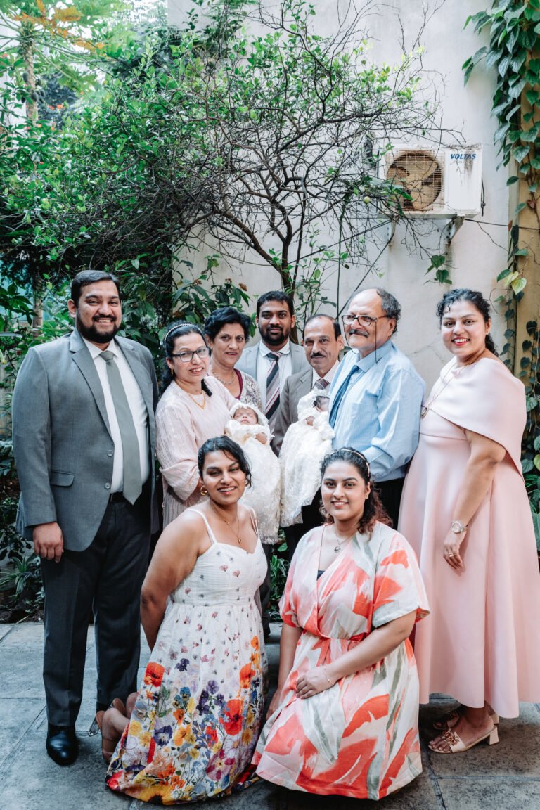 Three generations of a family posing for a portrait in their courtyard on a baptism day morning.