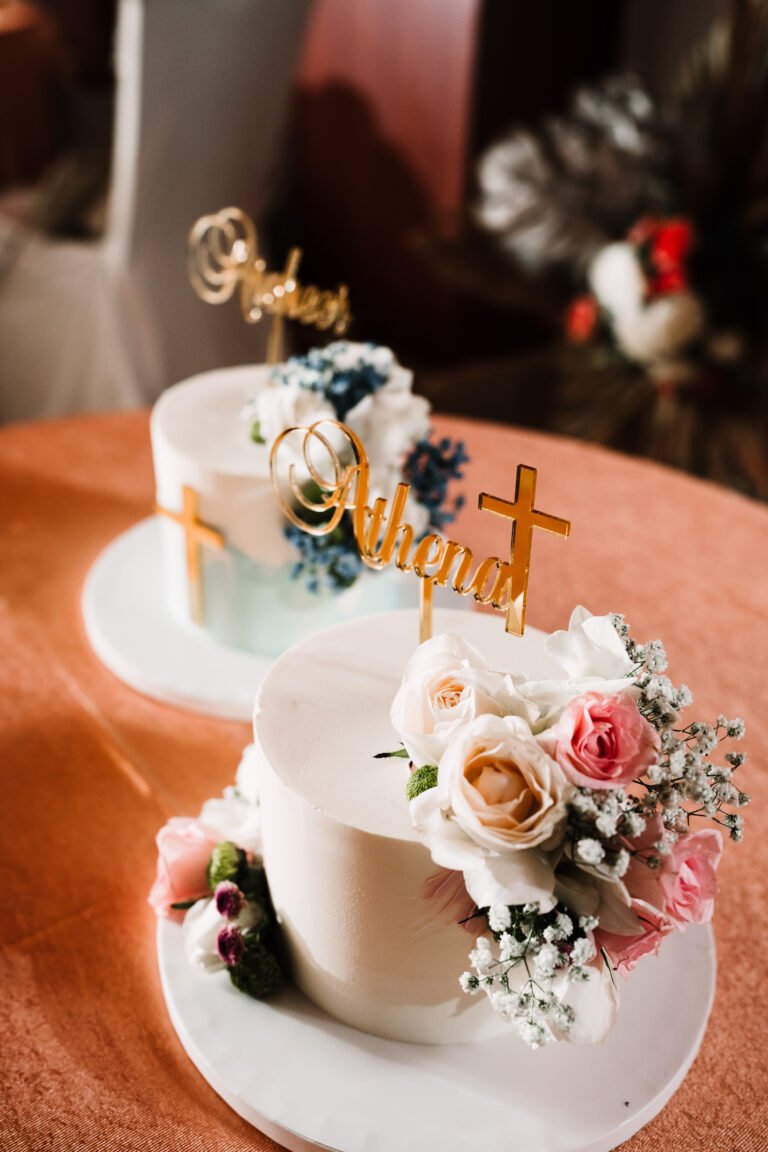 A baptism cake at a reception decorated with florals, featuring the baby's name as a cake topper