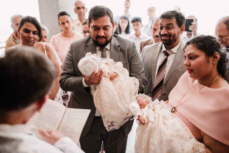 Parents holding twin babies at the entrance of a church, entering the altar for the baptism ceremony, capturing a solemn and meaningful moment.