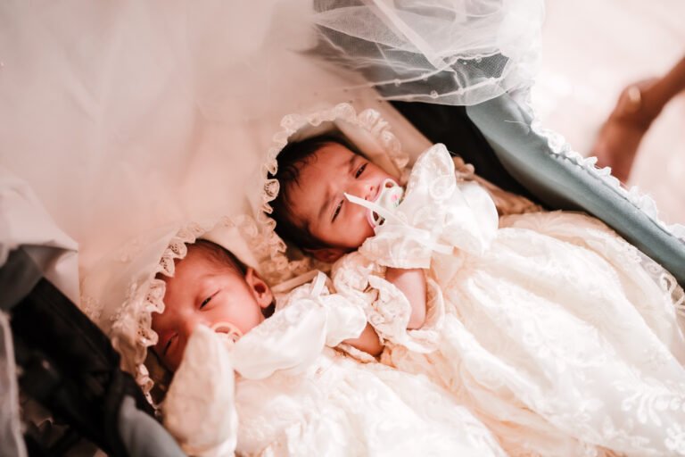 Twin babies cuddling together during their baptism reception ceremony