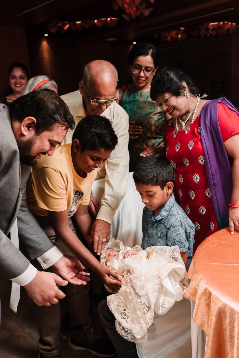 Young boy holding baby while the family attentively watching