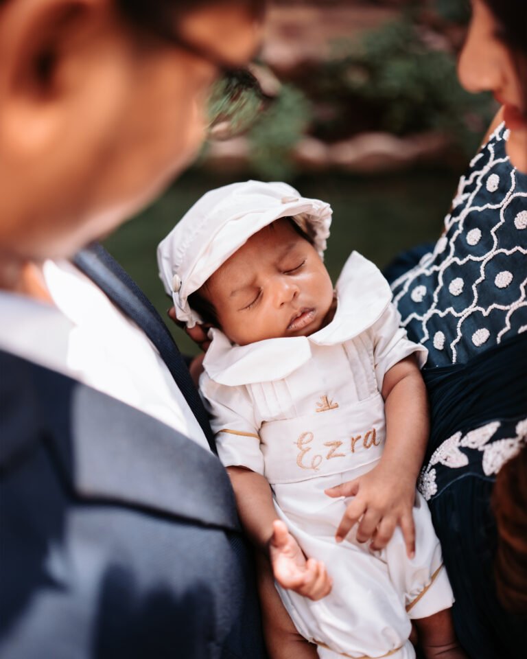 A baby sleeping peacefully held between their parents' arms