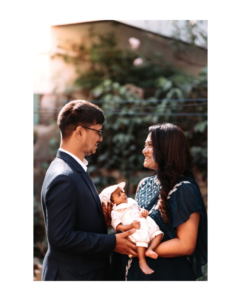 A candid image of parents smiling at each other while holding their newborn