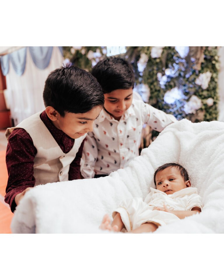 Children looking amazed at a newborn baby during baptism reception